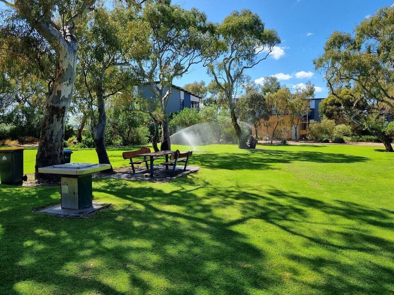 A park with a bench, a table, and a tree.