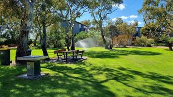 A park with a bench, a table, and a tree.