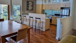A modern kitchen with a central island, wooden flooring, and a dining area with a table and chairs.