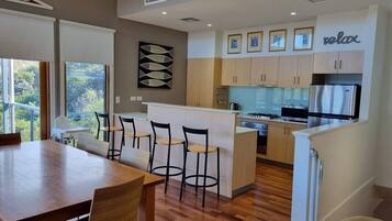 A modern kitchen with a central island, wooden flooring, and a dining area with a table and chairs.