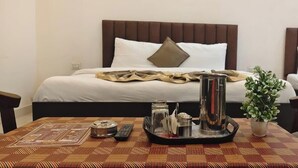 A hotel room with a bed, bedside table, and a small potted plant. - Shakuatulm Pravas (Bhimtal)
