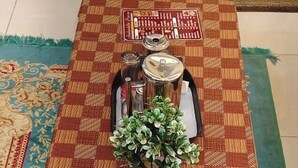 A dining table with a checkered tablecloth, a potted plant, and a set of cutlery. - Shakuatulm Pravas (Bhimtal)
