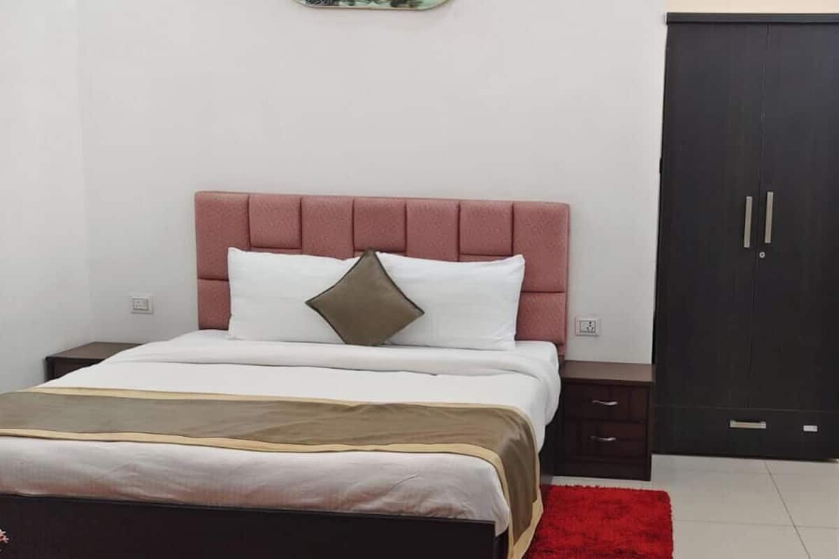 Un dormitorio con cama, armario, mesita de noche y una alfombra roja.