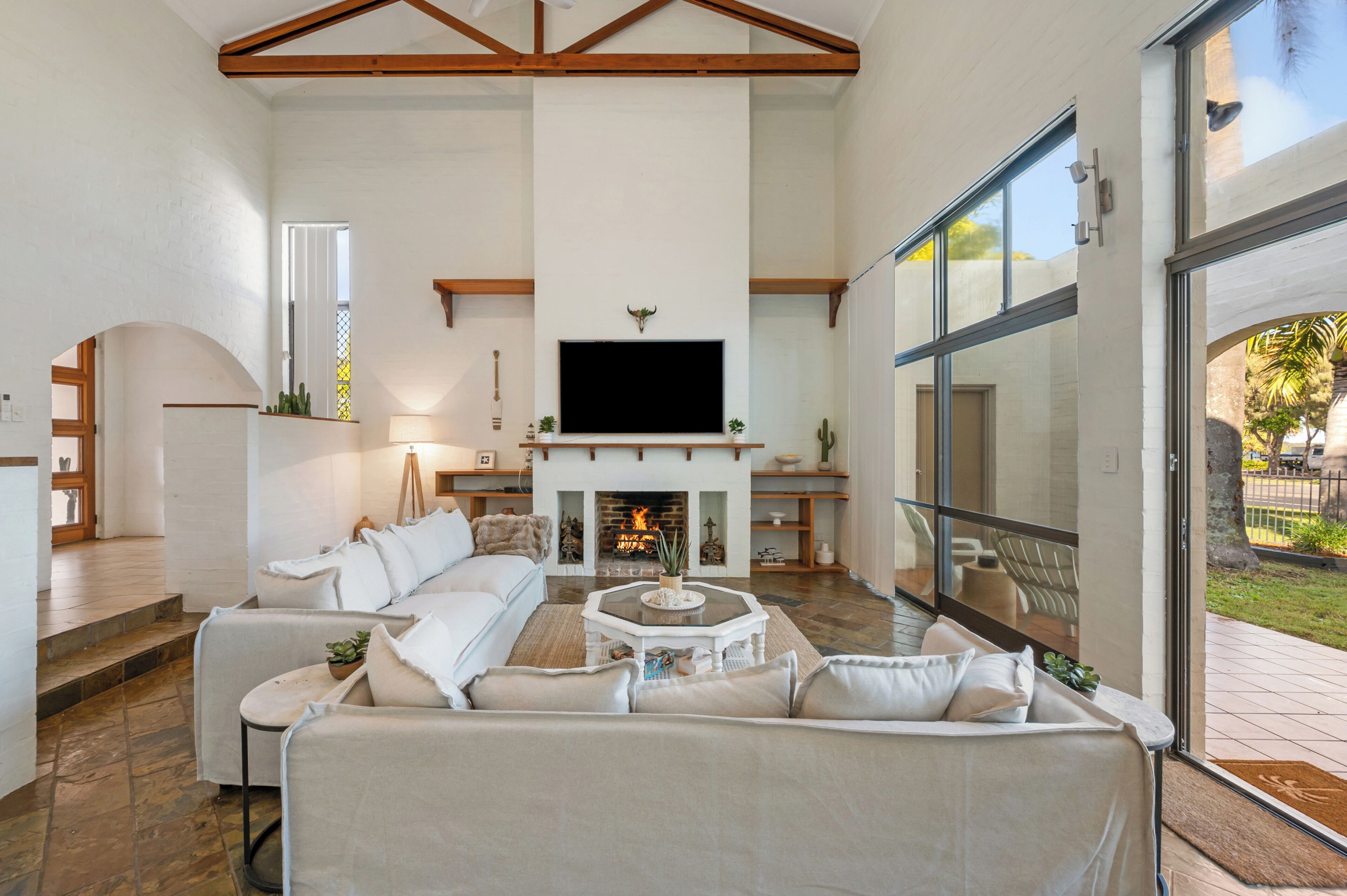 Bright living area with TV, fireplace and patio.
