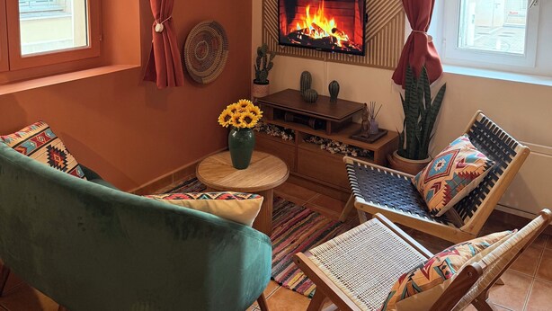 Un salon confortable avec une cheminée, un canapé, un fauteuil et un téléviseur.
