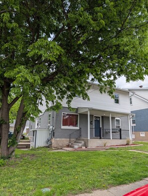 A residential house with a front porch, a garage, and a large tree in front. - Two-bedroom apartment downtown Jefferson City! (Jefferson City)