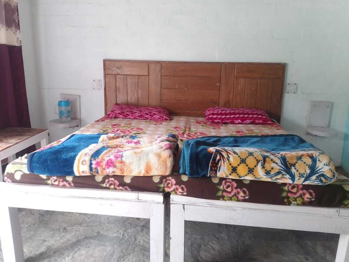 A bed with a wooden headboard, two pillows, and a floral bedspread.