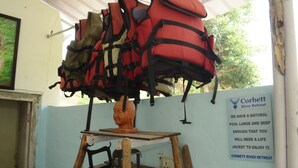 Um painel fixado na parede exibindo coletes salva-vidas e uma placa indicando Corbett River Retreat.