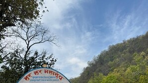 A pathway leading to a temple entrance with a signboard and a railing. - Raiseraa Cottages (Lansdowne)