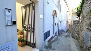 Un estrecho callejón con una entrada porticada, un buzón y una planta en maceta.