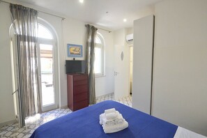 Ein Hotelzimmer mit einem Bett, einem Fernseher, einem Kleiderschrank und einer Tür zu einem anderen Raum.