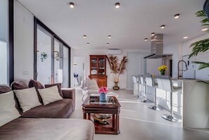 Ein modernes Wohnzimmer mit einer Couch, einem Couchtisch und einer Küchenzeile mit Barhocker.