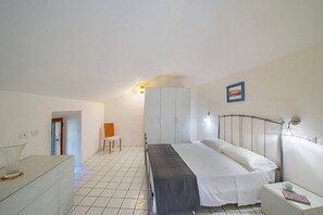 Ein Schlafzimmer mit Bett, Nachttisch, Kleiderschrank und einem kleinen Stuhl.