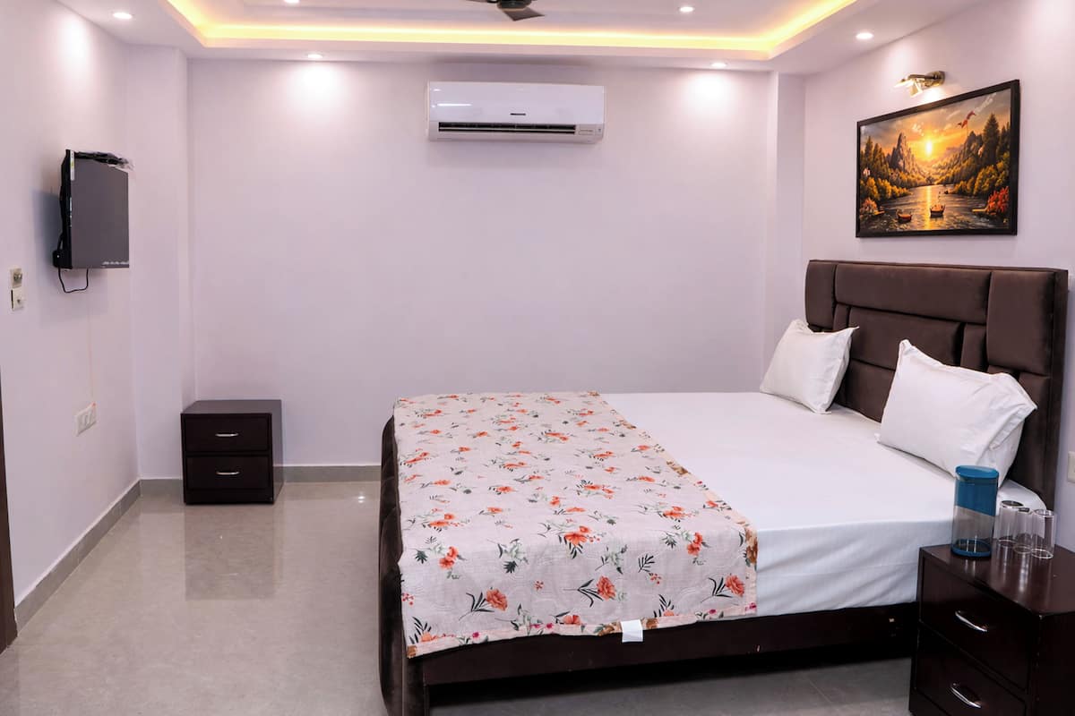Un dormitorio con cama, mesita de noche, aire acondicionado de pared y un cuadro en la pared.