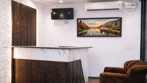 Una cocina moderna con encimera de mármol, un armario empotrado de madera, un televisor de pantalla plana y un equipo de aire acondicionado.