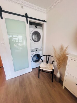 Ein Waschraum mit Schiebetür, einem Sessel, einer Vase mit Pampasgras und einem weißen Schrank.