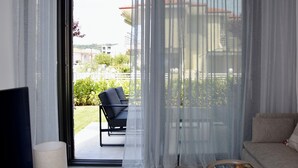 A modern living room with a sofa, a chair, a table with a book, and a TV. - Villa Elegance in Nikiti (Sithonia)