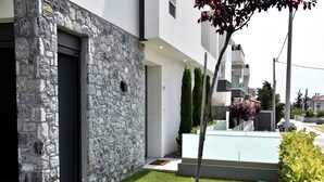 A modern building with a stone facade, a well-maintained lawn, and a clear view of the street. - Villa Elegance in Nikiti (Sithonia)