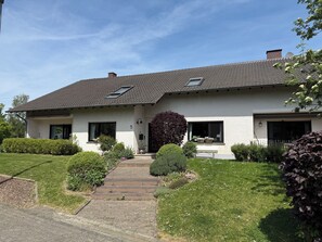 Ein zweistöckiges Haus mit einem Ziegeldach, einer Veranda und einem gepflegten Rasen.