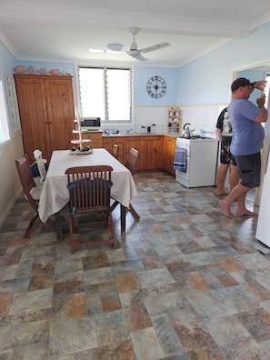 A kitchen with a dining table, chairs, a stove, and a clock on the wall. - House at Gatcombe Heads, Facing Island (Gladstone Harbour)