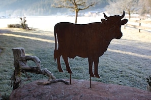 Eine Metall-Kuhskulptur auf einem Felsen vor einer natürlichen Landschaft.