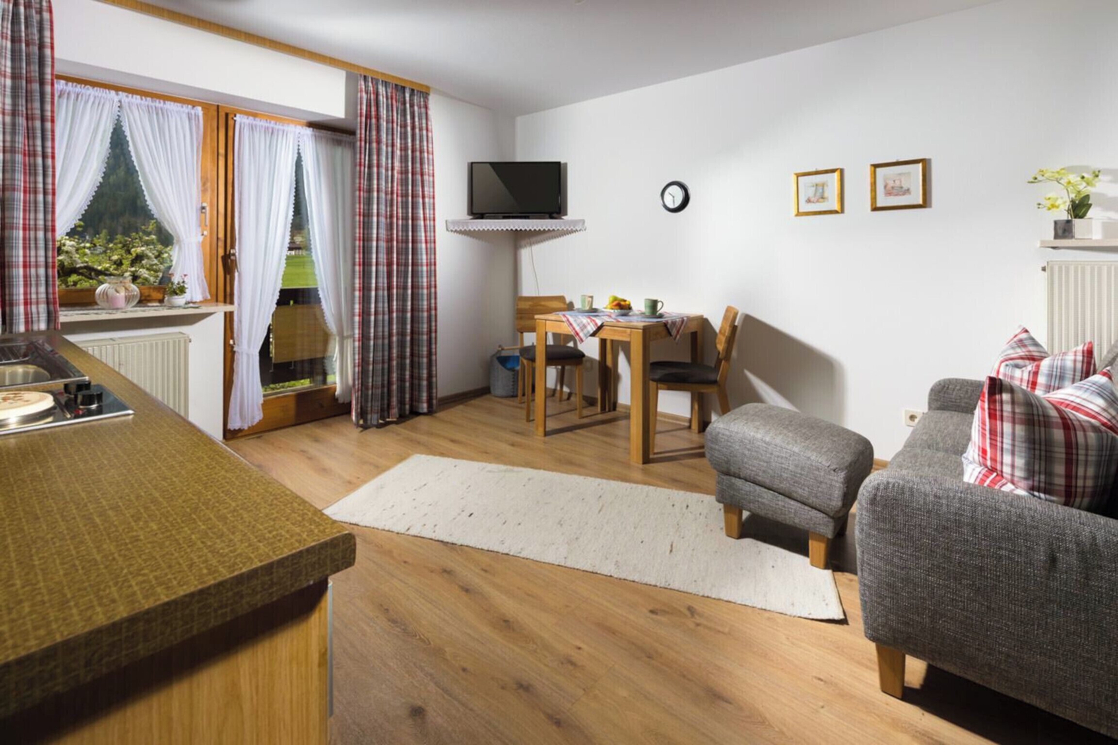 Ein gemütliches Wohnzimmer mit einer Couch, einem kleinen Tisch und einem an der Wand befestigten Fernseher.