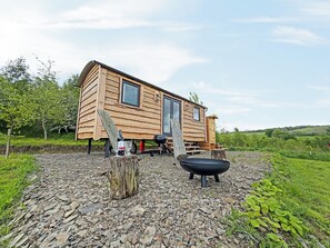 Een houten chalet met terras, buitenzitplaatsen en een barbecue.