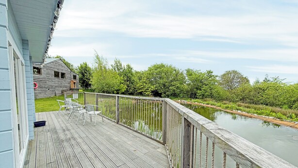 Een houten terras met stoelen, een klein gebouw en een rivier.