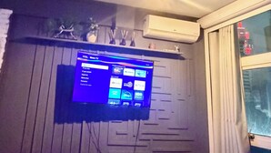 Uma sala de estar com televisão de tela plana na parede, lareira e duas poltronas de couro.
