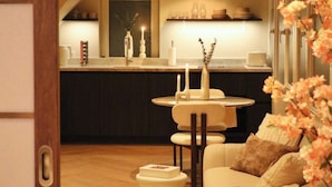 A cozy living room with a sofa, a small round table, and a kitchen in the background.