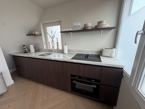 Una cocina moderna con horno integrado, un lavamanos y una ventana.