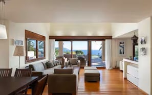 A spacious living area with a large window, a dining table, and a sofa. - Villa Valli Athenian Riviera, (Anavissos)
