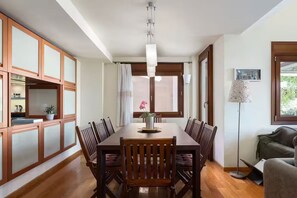 A dining area with a wooden table, chairs, a vase with flowers, and a pendant light. - Villa Valli Athenian Riviera, (Anavissos)