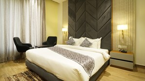 Een hotelkamer met een bed, twee bedlampen, een nachtkastje, een bureau en een stoel.
