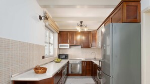 Una cocina con armarios de madera, un refrigerador de acero inoxidable, un microondas y un lavavajillas.