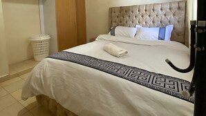 Una camera da letto con testiera trapuntata, un letto con biancheria bianca, un lampadario a sospensione e un armadio con ante in legno.