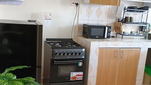 Una cucina con fornello, microonde, pensili e una pianta in vaso.