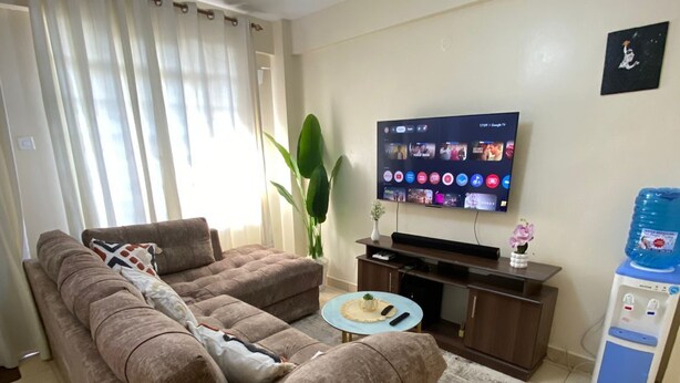 Un soggiorno con divano, televisore, un piccolo tavolino e un distributore d'acqua.