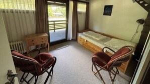 A room with a bed, a desk, two chairs, and a radiator. - Vacation apartment Knabenkraut 7 (Siegsdorf)