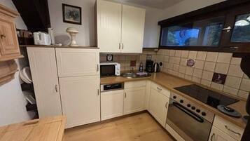 A compact kitchen with white cabinets, a microwave, a stove, and a wooden countertop.
