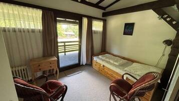 Ein Zimmer mit einem Bett, zwei Stühlen, einem Schreibtisch und einer Heizung.