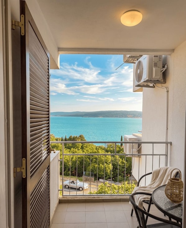 Ein Balkon mit Meerblick, ein Stuhl, ein Tisch und eine Klimaanlage.