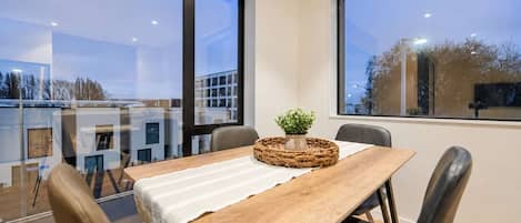 Un espace repas comprenant une table, des chaises et une vue dégagée grâce à de grandes fenêtres.