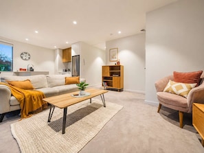 A modern living room with a sofa, a coffee table, and a bookshelf. - Central City Stay | 2BR + Balcony | Parking (Christchurch)