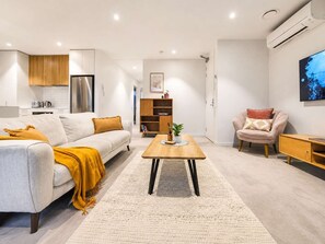 A modern living room with a sofa, coffee table, and a TV. - Central City Stay | 2BR + Balcony | Parking (Christchurch)