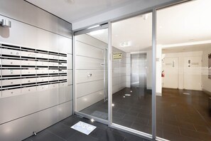 A modern hallway with lockers, a glass door, and a tiled floor. - South Yarra Retreat, Morning Hot Air Balloon Views (South Yarra)