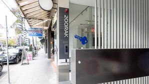 Un edificio moderno con fachada de vidrio, un cartel que dice '200RAK Residential Apartments' y un símbolo de llave azul que indica punto de acceso con llave electrónica.
