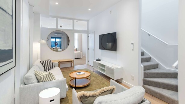 Un salon moderne avec un canapé, une table basse, un téléviseur et un escalier.