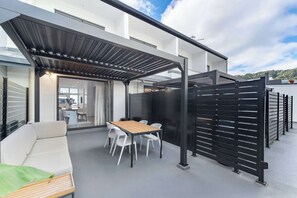 A modern outdoor patio with a table and chairs, a sofa, and a pergola structure. - The Hudson | 3BR Bright Courtenay Place Townhouse (Wellington)