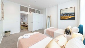 Une chambre moderne avec deux lits, une grande fenêtre et un tableau au mur.